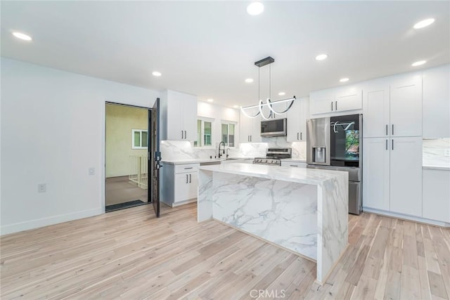 2143 Ronda Granada Unit P, Laguna Woods, CA 92637 - kitchen with stainless steel appliances, light wood finished floors, white cabinets, a center island, and recessed lighting