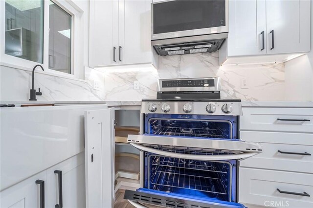 2143 Ronda Granada Unit P, Laguna Woods, CA 92637 - kitchen featuring stainless steel appliances, white cabinets, decorative backsplash, and glass insert cabinets