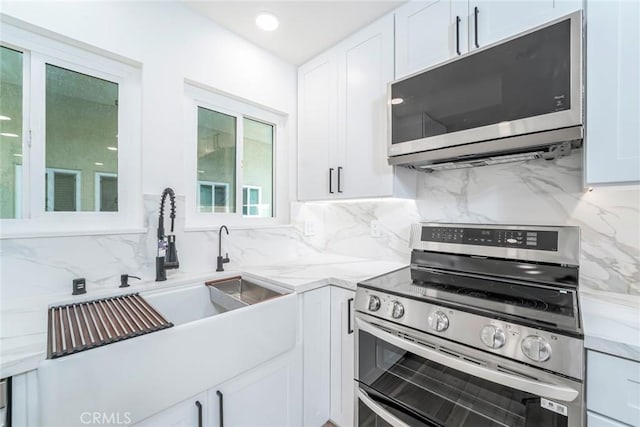 2143 Ronda Granada Unit P, Laguna Woods, CA 92637 - kitchen with stainless steel appliances, decorative backsplash, white cabinetry, and light stone counters
