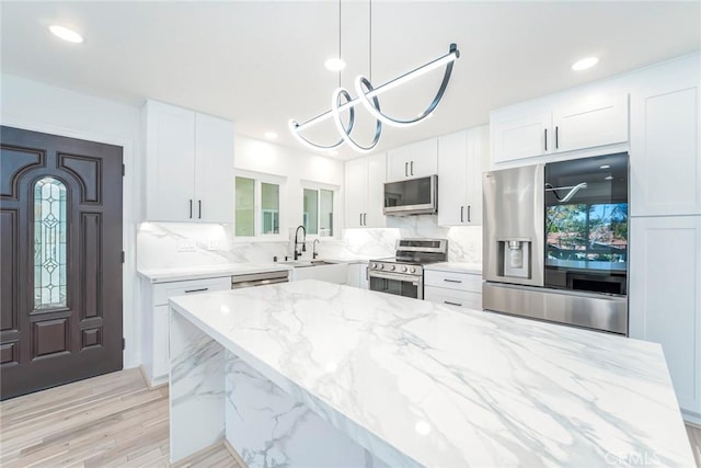 2143 Ronda Granada Unit P, Laguna Woods, CA 92637 - kitchen with appliances with stainless steel finishes, light stone counters, decorative backsplash, white cabinetry, and pendant lighting