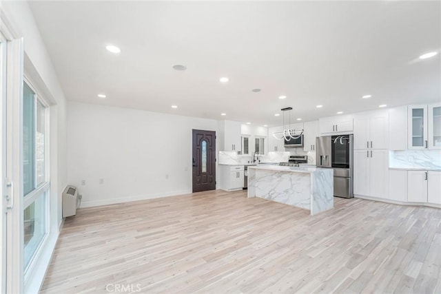 2143 Ronda Granada Unit P, Laguna Woods, CA 92637 - kitchen with stainless steel appliances, a center island, decorative backsplash, light wood finished floors, and recessed lighting