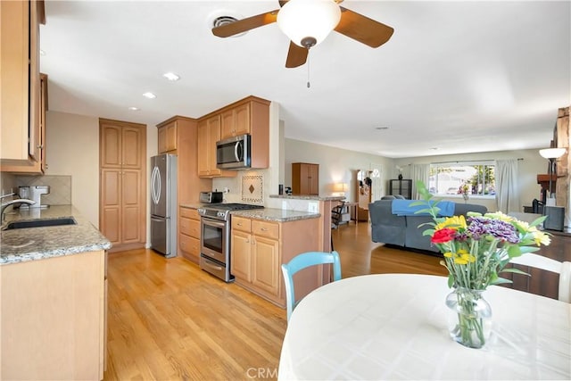 15041 Columbia Ln, Huntington Beach, CA 92647 - kitchen featuring stainless steel appliances, open floor plan, decorative backsplash, light wood-style flooring, and light stone counters