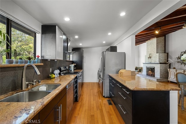 2920 Fairmount Ave, La Crescenta, CA 91214 - kitchen featuring appliances with stainless steel finishes, tasteful backsplash, a fireplace, light wood-style floors, and light stone countertops