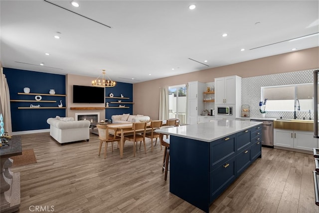 2920 Fairmount Ave, La Crescenta, CA 91214 - kitchen featuring stainless steel appliances, white cabinets, light wood-style flooring, backsplash, and blue cabinetry