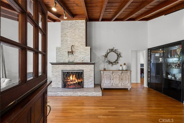 2920 Fairmount Ave, La Crescenta, CA 91214 - living area featuring a wooden ceiling with exposed beams, light wood finished floors, rail lighting, a towering ceiling, and a stone fireplace