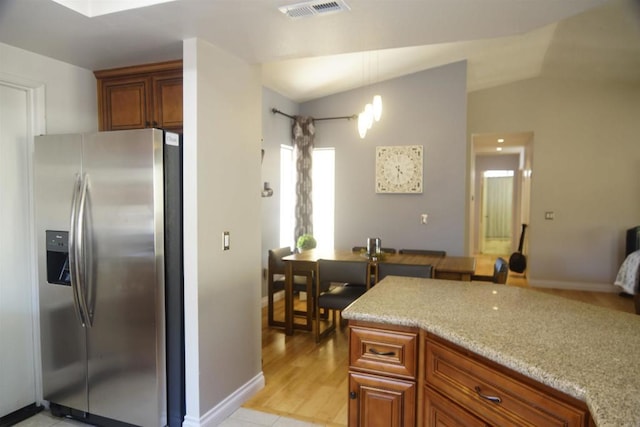 14330 Jennings Vista Way, Lakeside, CA 92040 - kitchen with stainless steel refrigerator with ice dispenser, brown cabinetry, light stone countertops, and lofted ceiling