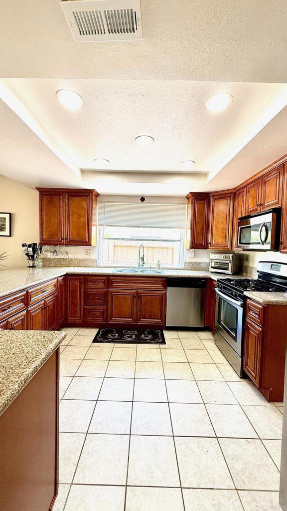 14330 Jennings Vista Way, Lakeside, CA 92040 - kitchen with appliances with stainless steel finishes, a raised ceiling, light tile patterned floors, recessed lighting, and a textured ceiling