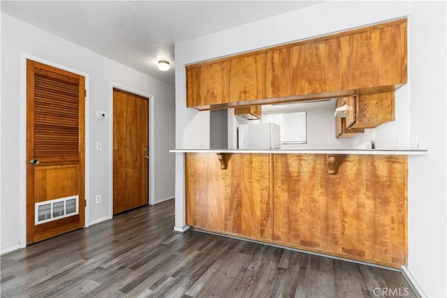 10710 El Camino Real Unit 14, Atascadero, CA 93422 - kitchen with brown cabinets, dark wood-type flooring, freestanding refrigerator, and light countertops