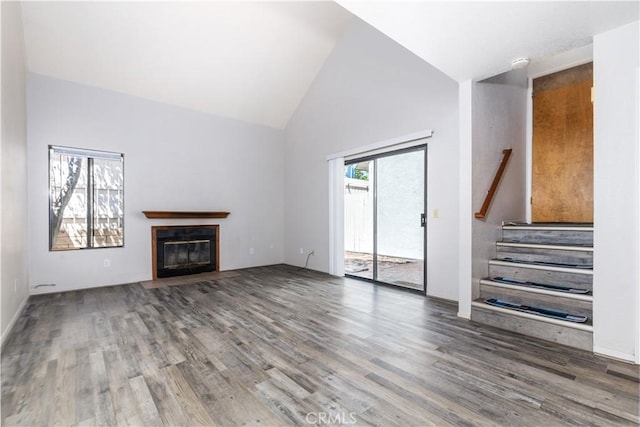 10710 El Camino Real Unit 14, Atascadero, CA 93422 - unfurnished living room featuring wood finished floors, a fireplace with flush hearth, high vaulted ceiling, and stairway