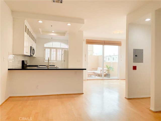 1628 E Palm Ave Unit 5, El Segundo, CA 90245 - kitchen with electric panel, stainless steel microwave, light wood-style flooring, freestanding refrigerator, and white cabinetry