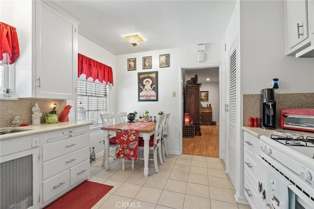 35 Columbia St, Pasadena, CA 91105 - kitchen featuring white gas range oven, tasteful backsplash, light countertops, light tile patterned floors, and white cabinetry