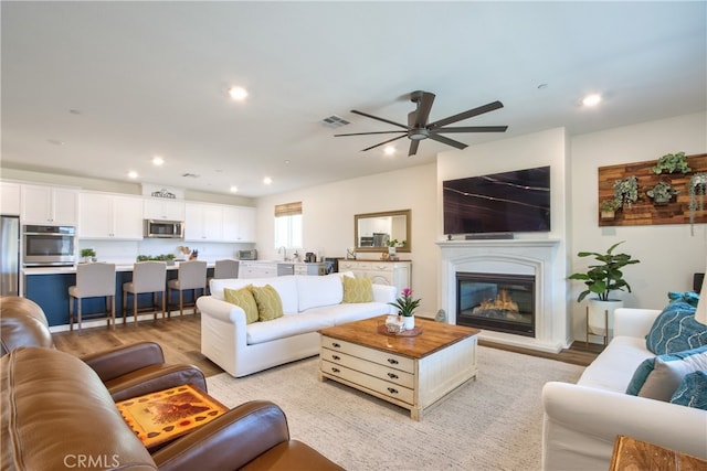 33084 Toledo Bend Ct, Winchester, CA 92596 - living room featuring recessed lighting, a ceiling fan, light wood-type flooring, and a glass covered fireplace
