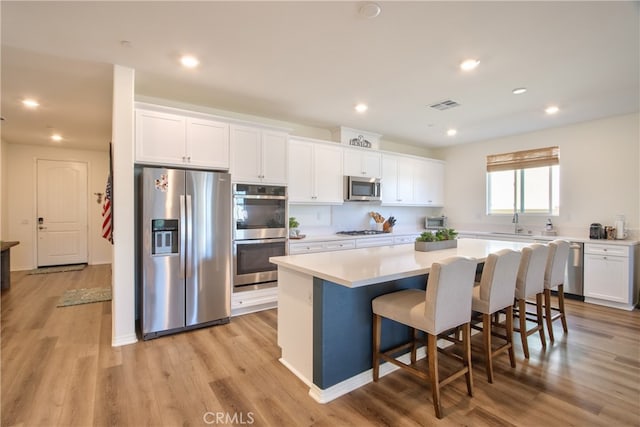 33084 Toledo Bend Ct, Winchester, CA 92596 - kitchen featuring stainless steel appliances, white cabinetry, a center island, light wood finished floors, and recessed lighting