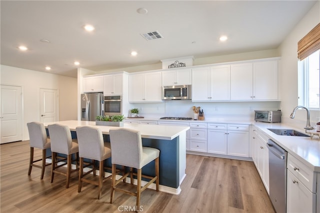 33084 Toledo Bend Ct, Winchester, CA 92596 - kitchen with stainless steel appliances, a center island, white cabinets, light wood finished floors, and recessed lighting