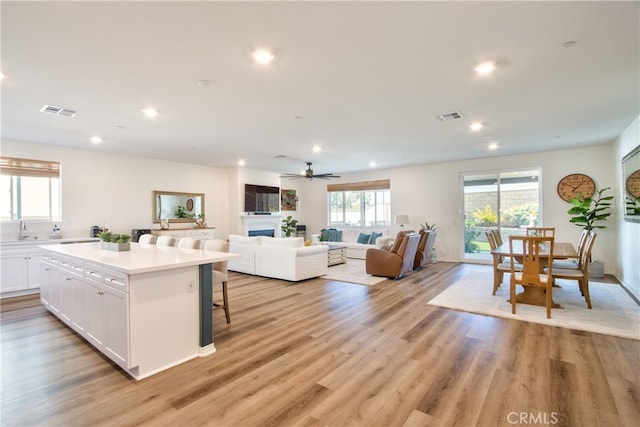 33084 Toledo Bend Ct, Winchester, CA 92596 - kitchen with white cabinetry, recessed lighting, a center island, a kitchen bar, and light wood finished floors