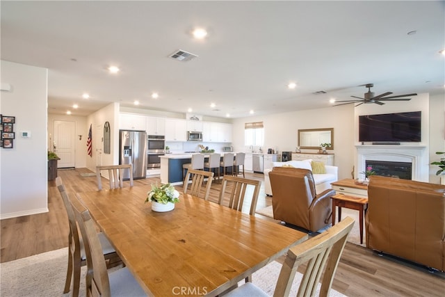 33084 Toledo Bend Ct, Winchester, CA 92596 - dining room featuring light wood finished floors, a fireplace, a ceiling fan, and recessed lighting
