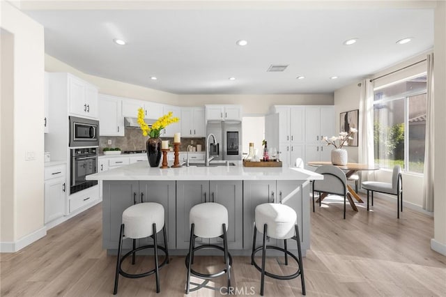 18680 Vantage Pointe Dr, Rowland Heights, CA 91748 - kitchen with appliances with stainless steel finishes, white cabinets, light countertops, a kitchen bar, and recessed lighting