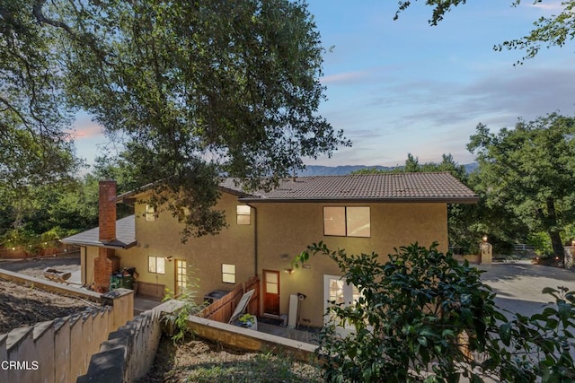 2100 Valley Meadow Dr, Oak View, CA 93022 - back of house at dusk with stucco siding, a tile roof, and a chimney
