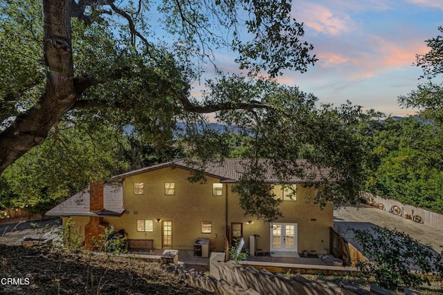 2100 Valley Meadow Dr, Oak View, CA 93022 - back of property at dusk with french doors, stucco siding, a chimney, and a patio