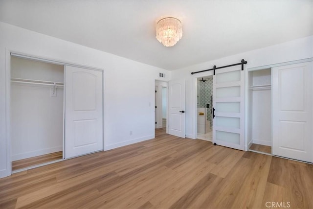 11251 Bowles Ave, Garden Grove, CA 92841 - unfurnished bedroom featuring light wood-style floors, multiple closets, and a barn door