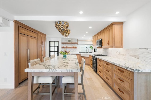 1817 W Bay Ave Unit A, Newport Beach, CA 92663 - kitchen with high end appliances, open shelves, light wood-style floors, a kitchen breakfast bar, and backsplash