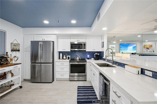 200 Pacific Coast Unit 130, Huntington Beach, CA 92648 - kitchen with appliances with stainless steel finishes, a ceiling fan, a peninsula, white cabinets, and tasteful backsplash
