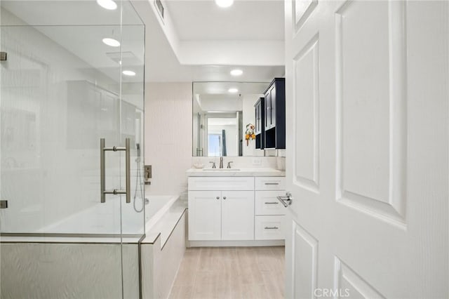 200 Pacific Coast Unit 130, Huntington Beach, CA 92648 - full bathroom with vanity, a shower stall, a garden tub, recessed lighting, and wood finished floors