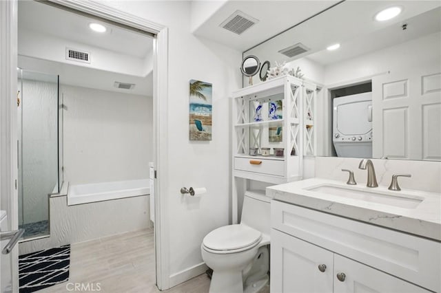 200 Pacific Coast Unit 130, Huntington Beach, CA 92648 - bathroom with stacked washer / drying machine, vanity, a bath, wood finished floors, and a stall shower