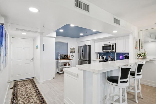200 Pacific Coast Unit 130, Huntington Beach, CA 92648 - kitchen with appliances with stainless steel finishes, a peninsula, light countertops, white cabinets, and a kitchen breakfast bar