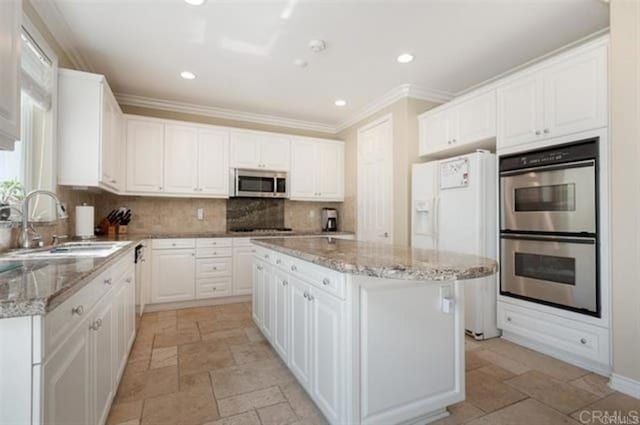 2792 Rambling Vistas Rd, Chula Vista, CA 91915 - kitchen with stainless steel appliances, stone tile floors, a center island, white cabinetry, and crown molding