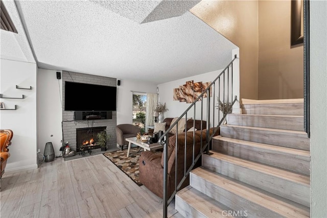 15060 Chatsworth St Unit E, San Fernando, CA 91345 - living room with a fireplace, wood finished floors, stairs, and a textured ceiling