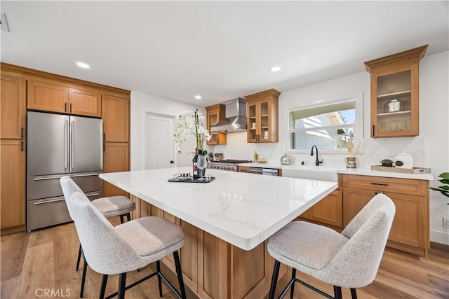 1809 Celeste Ln, Fullerton, CA 92833 - kitchen featuring stainless steel appliances, wall chimney range hood, a center island, light wood-style flooring, and glass insert cabinets
