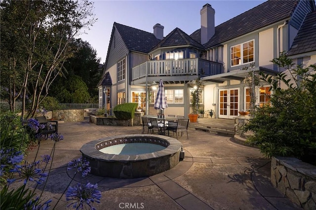 31681 Peppertree, San Juan Capistrano, CA 92675 - back of property at dusk featuring french doors, a balcony, a patio, an in-ground hot tub, and stucco siding