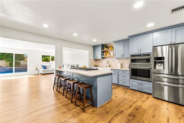 8110 True Ave, Pico Rivera, CA 90660 - kitchen with appliances with stainless steel finishes, open shelves, gray cabinets, a breakfast bar, and tasteful backsplash