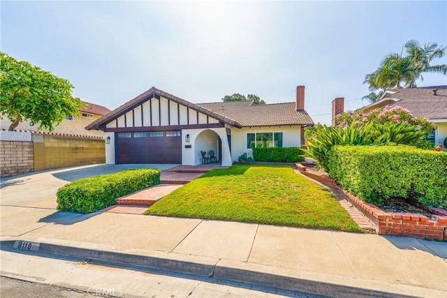 8110 True Ave, Pico Rivera, CA 90660 - tudor-style house with driveway, a chimney, an attached garage, stucco siding, and a tiled roof