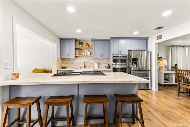 8110 True Ave, Pico Rivera, CA 90660 - kitchen with stainless steel appliances, gray cabinets, a breakfast bar, backsplash, and light stone counters