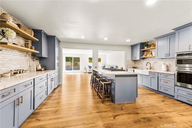 8110 True Ave, Pico Rivera, CA 90660 - kitchen featuring open shelves, a breakfast bar area, appliances with stainless steel finishes, light countertops, and backsplash