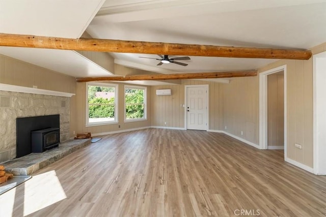 1212 N Old Stage Rd, Mount Shasta, CA 96067 - unfurnished living room with wood finished floors, beam ceiling, a wood stove, a ceiling fan, and a wall mounted air conditioner