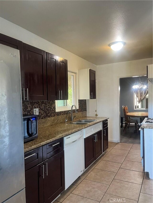 5617 29th St, Jurupa Valley, CA 92509 - kitchen featuring freestanding refrigerator, dishwasher, backsplash, light tile patterned floors, and dark stone counters
