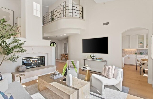 7 Suprema Dr, Newport Coast, CA 92657 - living room with a high ceiling, light wood-style floors, arched walkways, and a premium fireplace