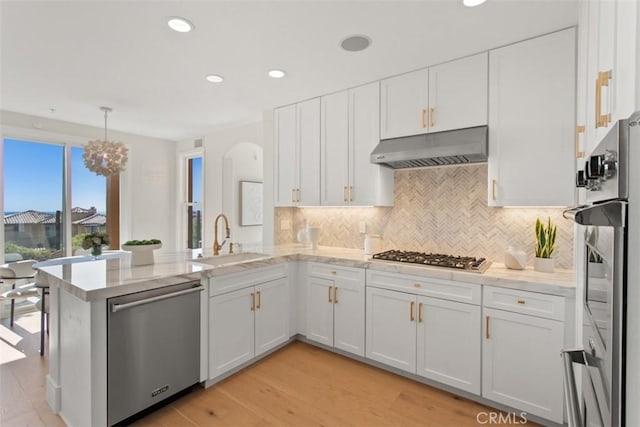 7 Suprema Dr, Newport Coast, CA 92657 - kitchen featuring stainless steel appliances, under cabinet range hood, a peninsula, white cabinets, and tasteful backsplash