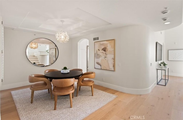 7 Suprema Dr, Newport Coast, CA 92657 - dining room with arched walkways, light wood-style floors, a raised ceiling, and a chandelier