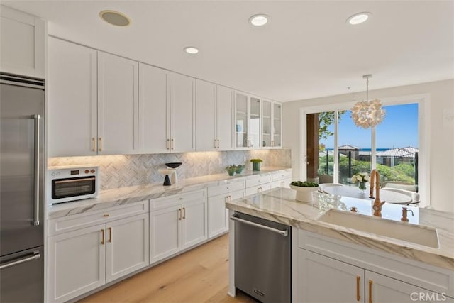 7 Suprema Dr, Newport Coast, CA 92657 - kitchen featuring appliances with stainless steel finishes, white cabinetry, decorative backsplash, glass insert cabinets, and light wood-type flooring