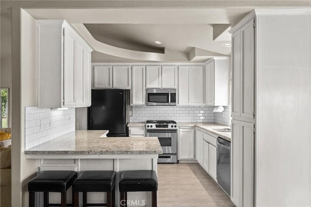 825 Rosana Pl, Nipomo, CA 93444 - kitchen with stainless steel appliances, a peninsula, backsplash, light wood-type flooring, and white cabinetry