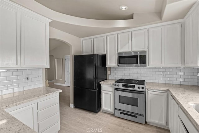 825 Rosana Pl, Nipomo, CA 93444 - kitchen with appliances with stainless steel finishes, arched walkways, backsplash, light stone counters, and white cabinetry