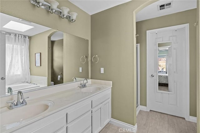 825 Rosana Pl, Nipomo, CA 93444 - full bathroom with double vanity, a skylight, a garden tub, wood finished floors, and a shower with door
