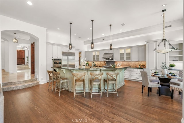1337 8th St, Manhattan Beach, CA 90266 - kitchen with stainless steel appliances, under cabinet range hood, tasteful backsplash, arched walkways, and a breakfast bar