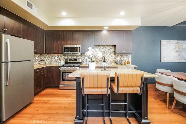 1002 Leighton Ave, Los Angeles, CA 90037 - kitchen featuring stainless steel appliances, light countertops, light wood-type flooring, dark brown cabinetry, and recessed lighting