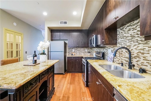 1002 Leighton Ave, Los Angeles, CA 90037 - kitchen featuring stainless steel appliances, light wood finished floors, decorative backsplash, light stone countertops, and dark brown cabinetry