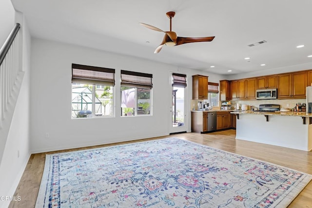 665 Tiber River Way, Oxnard, CA 93036 - kitchen with stainless steel appliances, a breakfast bar area, ceiling fan, light stone countertops, and brown cabinets